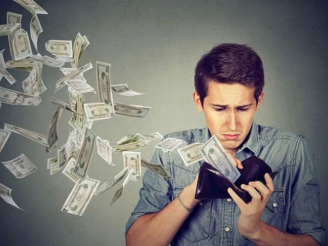Person checking finances as money flies around, illustrating cost leakage from duplicate records, overstocking, and unnecessary purchases.